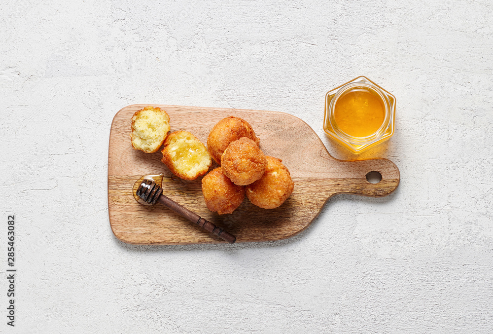 Cottage cheese balls doughnuts is jam-packed with jelly filling on wooden cut board and glass jar honey