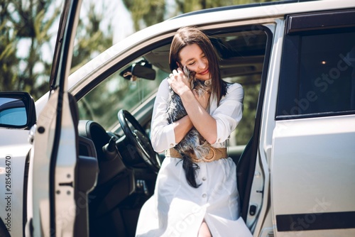 Very beautiful girl with a pretty dog near a luxury car