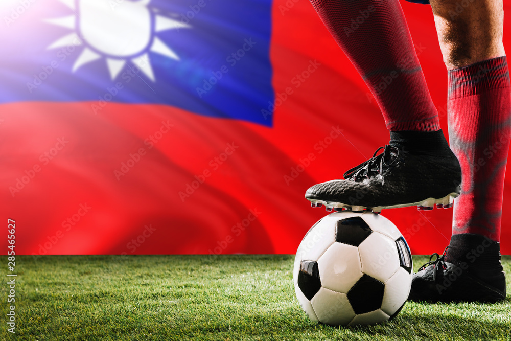 Close up legs of Taiwan football team player in red socks, shoes on soccer ball at the free kick or penalty spot playing on grass.