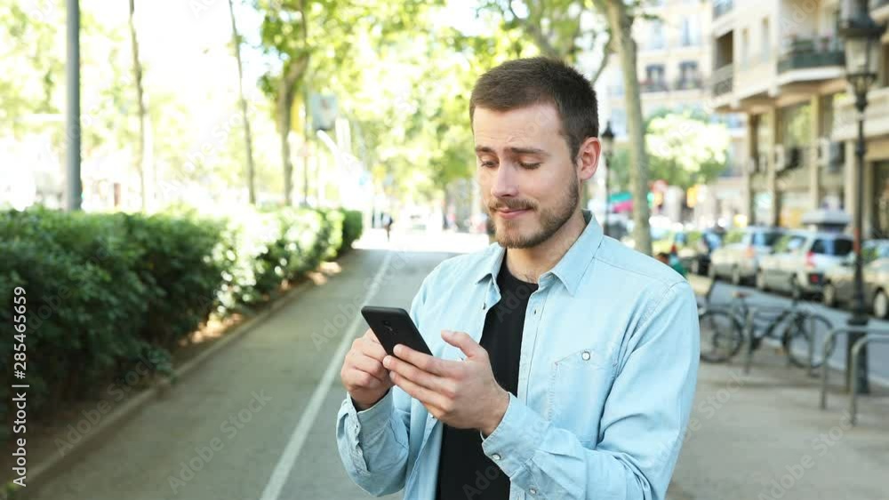Man using smart phone and saying yes looking at camera in the street Man using smart phone and saying yes looking at camera in the street