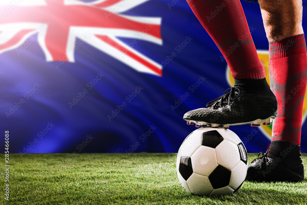 Close up legs of Turks And Caicos Islands football team player in red socks, shoes on soccer ball at the free kick or penalty spot playing on grass.