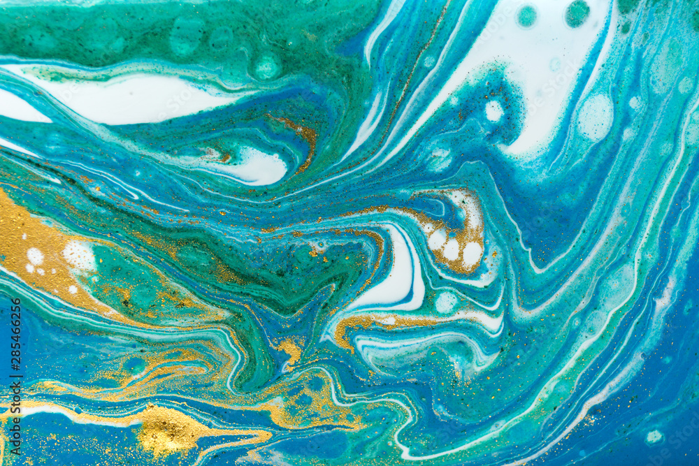 Liquid uneven blue and green marbling pattern with golden glitter and glare of light. Liquid uneven blue and green marbling pattern with golden glitter and glare of light.