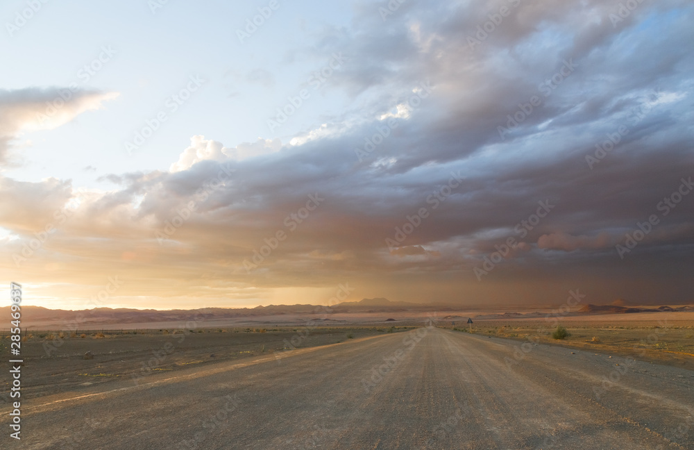 Road in the desert with storm clouds in the sunset