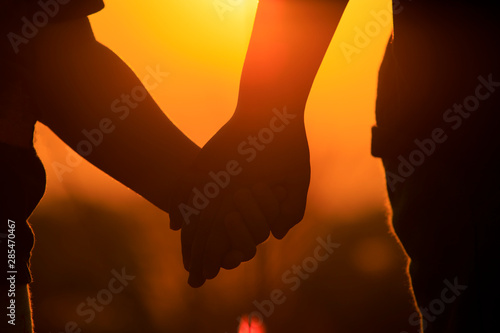 (Close up)Silhouette of portrait of a couple holding hands in the sunset,Children holding hands and looking at the sunset,Children and nature concept