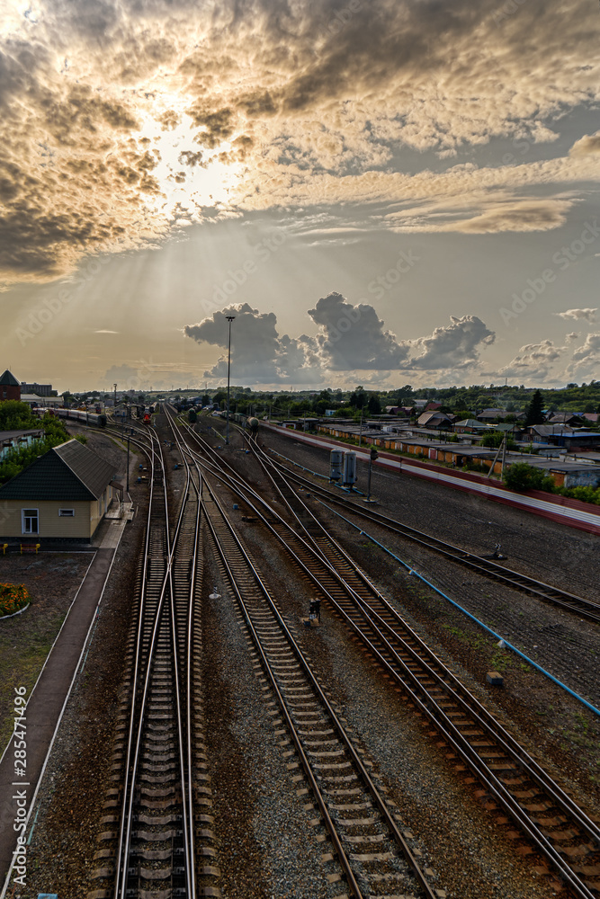 Fototapeta premium View of the railway tracks going into the distance. The sky before sunset with clouds