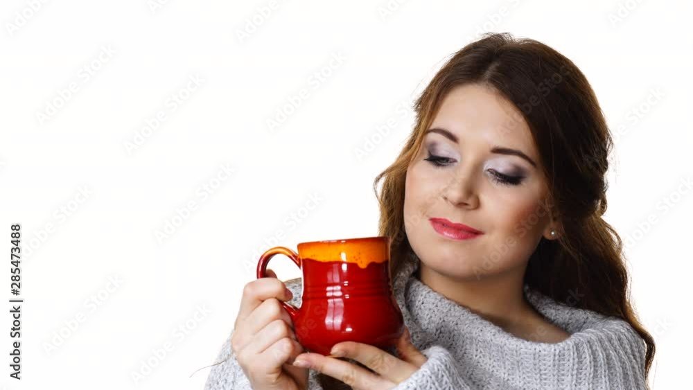 Woman wearing warm clothing grey sweater holding nice red mug of warm beverage tea or coffee, isolated on white Woman wearing warm clothing grey sweater holding nice red mug of warm beverage tea or coffee, isolated on white