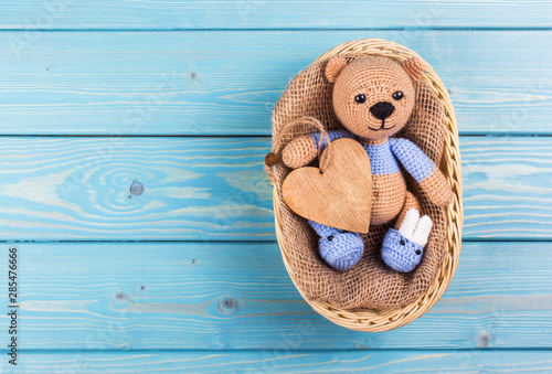 Little crocheted teddy bear on wooden background. Teddy bear and heart. Teddy bear copy space