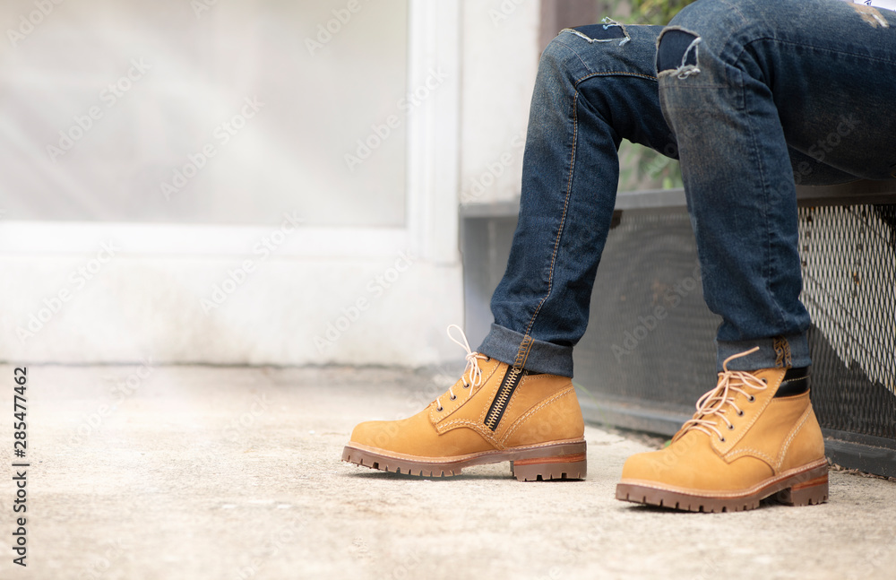The men model wearing jeans and yellow boots leather with zipper for man  collection. Stock Photo | Adobe Stock