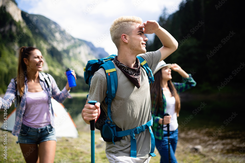 Naklejka premium Group of happy friends with backpacks hiking together