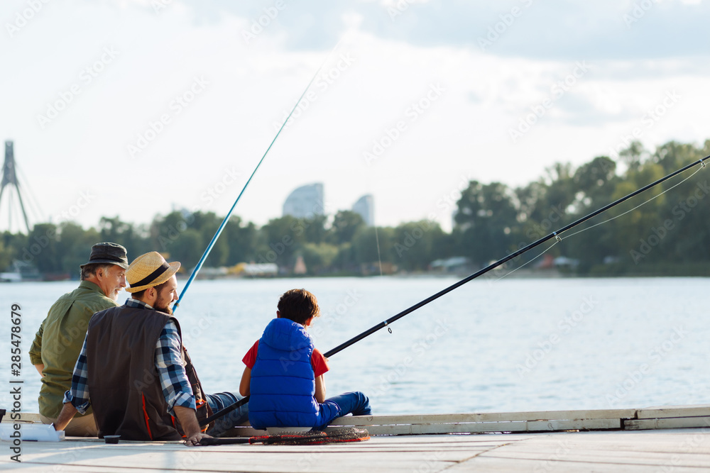 Boy feeling memorable while fishing with dad and granddad Boy feeling memorable while fishing with dad and granddad