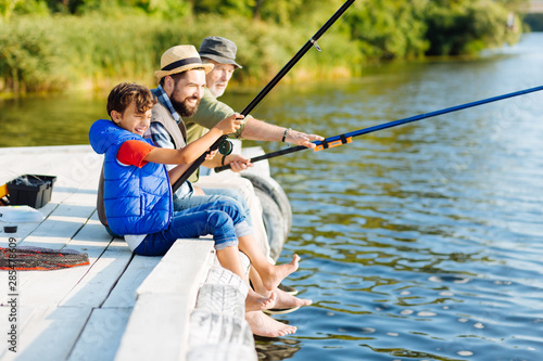 Men of three generations feeling happy while fishing in summer