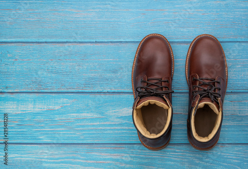 Men fashion of brown boot on blue wooden background. Flat lay, top view