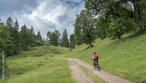 active senior woman on her electric mountain bike in the old Maple tree forest of the Nagelfluh chain near Obertstaufen, Allgaeu mountains, 