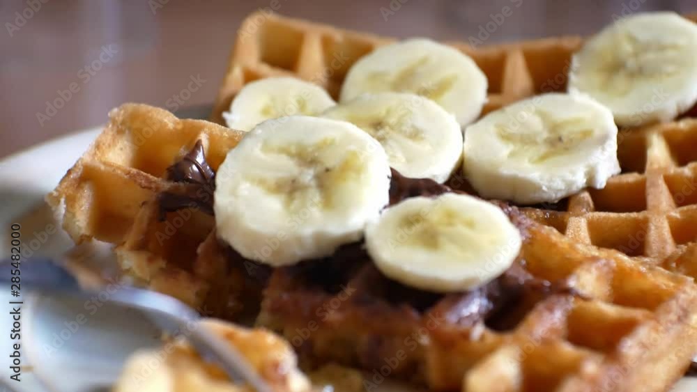 Delicious golden crispy waffles with chopped banana, chocolate maple syrup foodstuff. Close up pan. Delicious golden crispy waffles with chopped banana, chocolate maple syrup foodstuff. Close up pan.