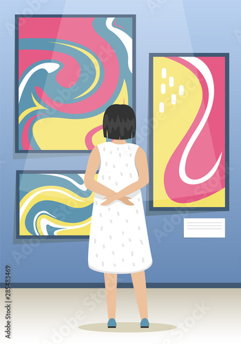 The girl looks the paintings of modern abstract artists. Modern Art Museum. Biennale of contemporary art. Minimalistic interior of the Museum.