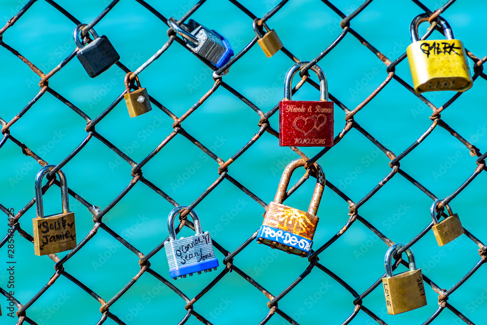 Colorful labeled padlocks/ locks locked on fence. Romantic relationship couples with names & special dates in writing. Love celebration and symbol of agreement, security, cherished moments and people. Colorful labeled padlocks/ locks locked on fence. Romantic relationship couples with names & special dates in writing. Love celebration and symbol of agreement, security, cherished moments and people.