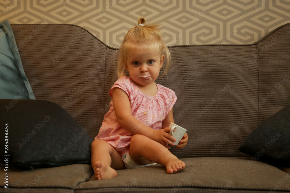 Indoor portrait of a little infant girl drinking milk from the ceramic cup Indoor portrait of a little infant girl drinking milk from the ceramic cup
