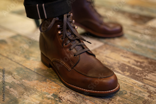 Brown leather men’s boots on legs closeup view