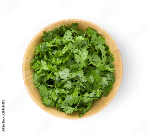 coriander in wood bowl isolated on white background. top view