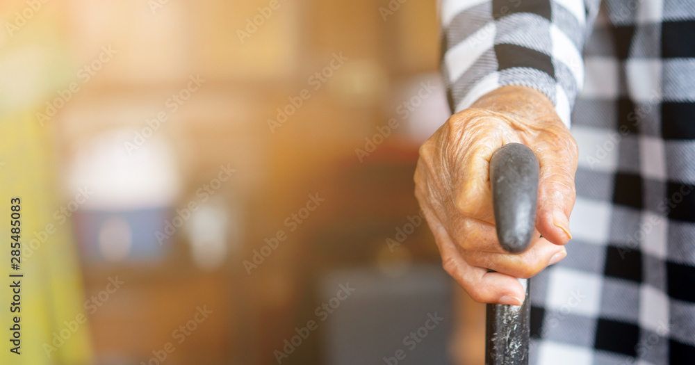 closeup senior woman hand holding walking cane to help stand at home , lifestyle of aging people concept