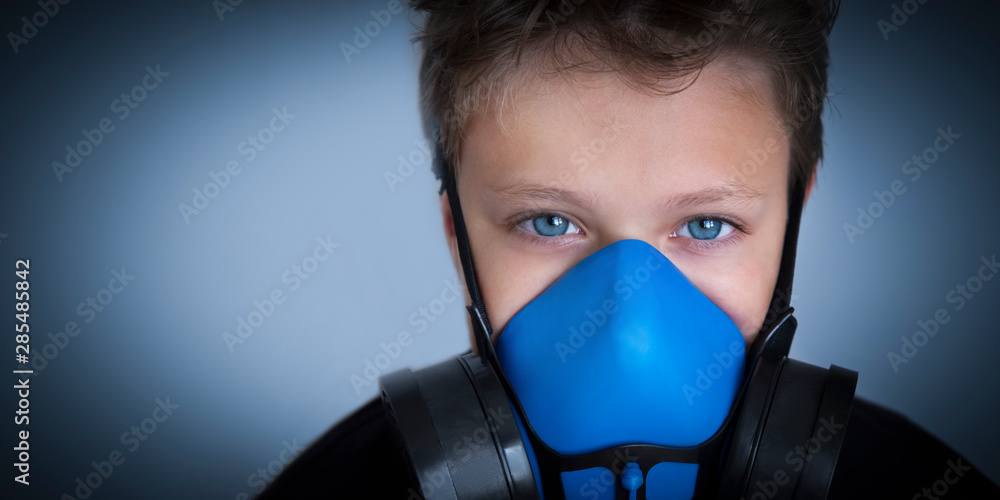 Young boy wearing gasmask, respirator portrait. Effects of worldwide air pollution, industrial influence on environment. Protection from dangerous air particles, gas, smog, transmitted diseases Young boy wearing gasmask, respirator portrait. Effects of worldwide air pollution, industrial influence on environment. Protection from dangerous air particles, gas, smog, transmitted diseases