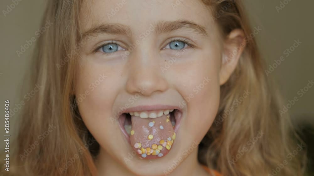A child is smiling with a mouth full of candy. Little girl eating candy