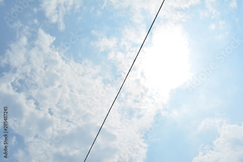 cable cruzando el cielo azul con nubes blancas y sol brillante