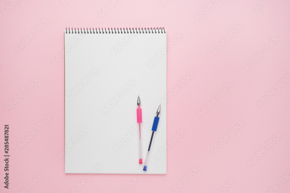 Spiral notepad with pens. Notebook on pastel pink backdrop. Back to school concept. opy space, top view.
