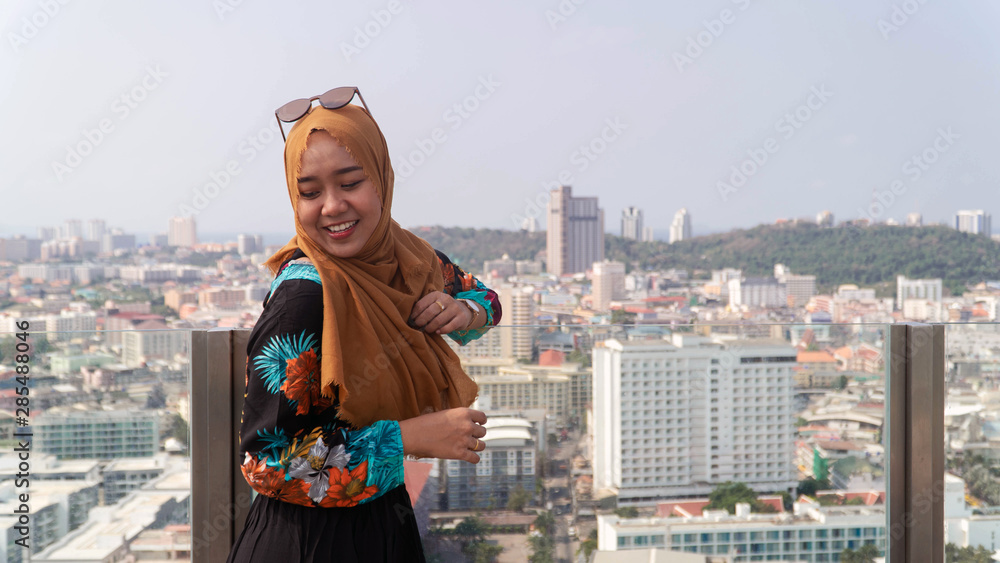 Outdoors lifestyle fashion portrait of pretty muslim woman with hijab walking on the roof. Enjoying summer.