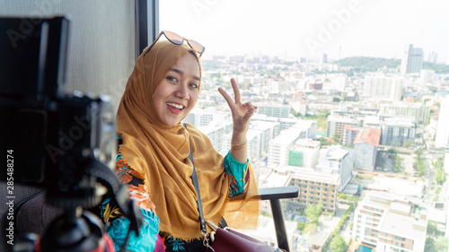 portrait of beautiful Muslim woman with hijab taking video vlog Against View Of The City