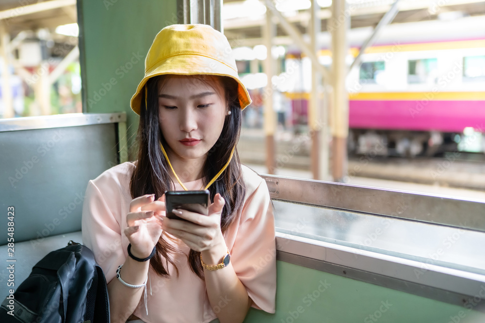 Young Asian woman using her mobile phone while sitting in the train