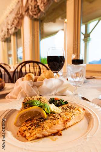 Salmon dinner on a white plate with a glass of red wine. photo