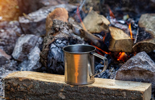 steel cup on an open fire in nature. Cooking on fire. Camping in summer.