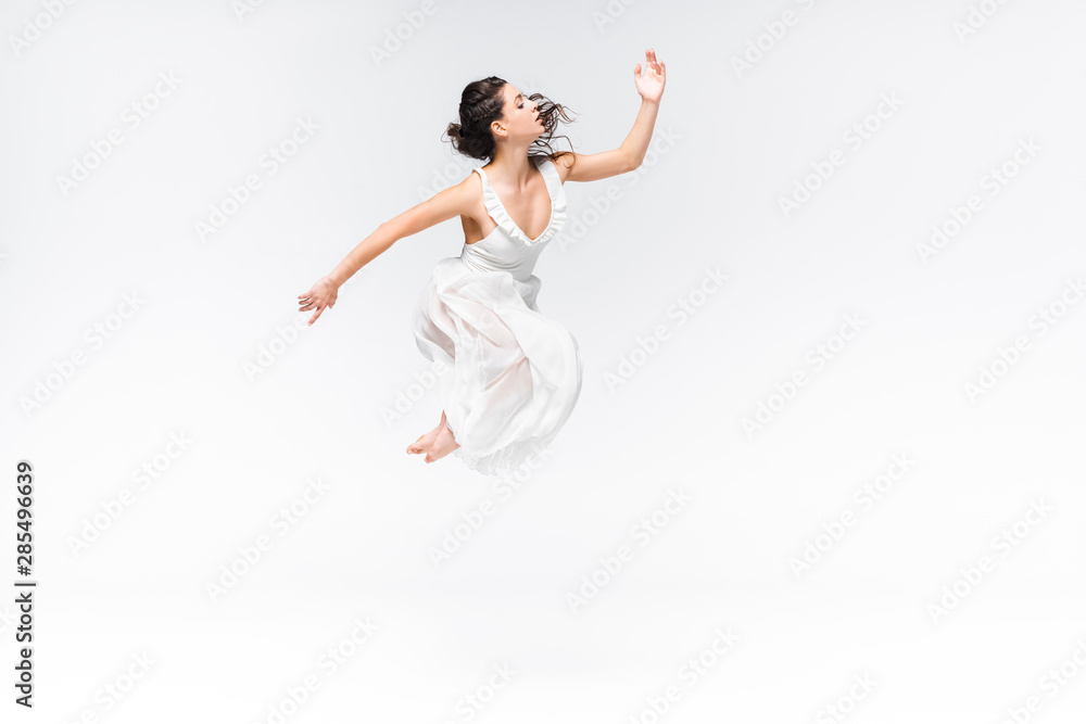 beautiful, graceful ballerina jumping in dance on grey background