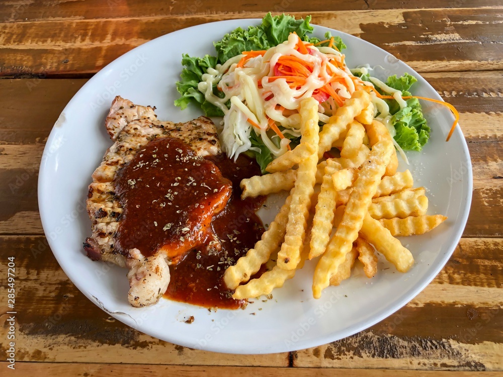 Pork steak with potato fried and salad on the wood table Pork steak with potato fried and salad on the wood table