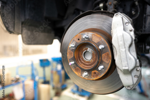 Close up of Brake Disc of the vehicle for repair.Automobile mechanic in process of new tire replacement.Car brake repairing in garage.Car Service and technician concept.
