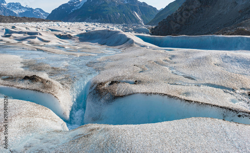 closeup of a crevasse in the gilkey glacier in alaska with rugged mountains in the background