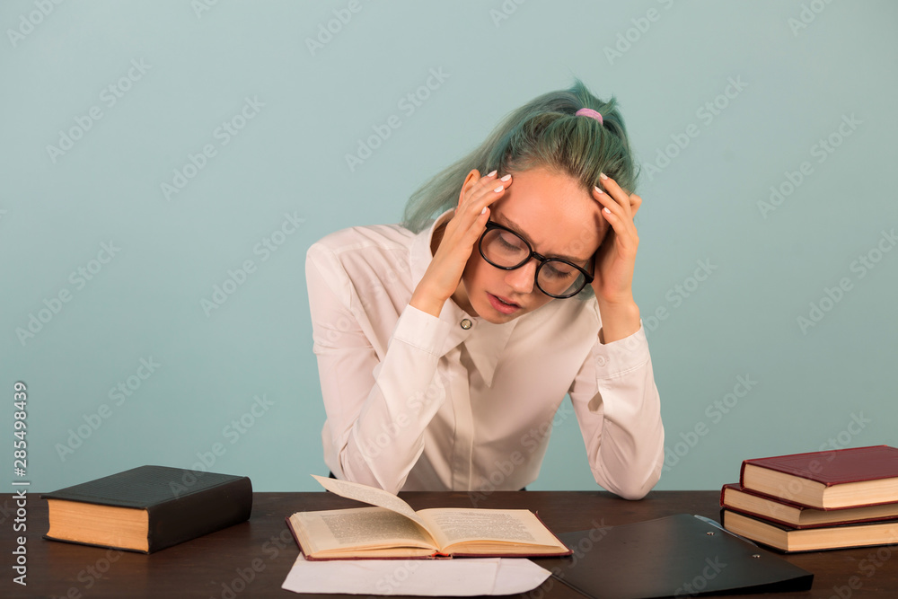 beautiful young woman in glasses sits at a table with books beautiful young woman in glasses sits at a table with books