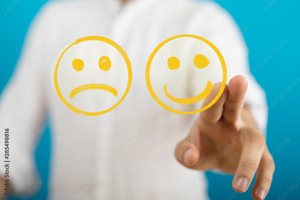 Hand is selecting a happy mood smiley. In front of an empty room Hand is selecting a happy mood smiley. In front of an empty room