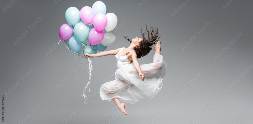 panoramic shot of graceful ballerina dancing with festive balloons on grey background - obrazy, fototapety, plakaty 