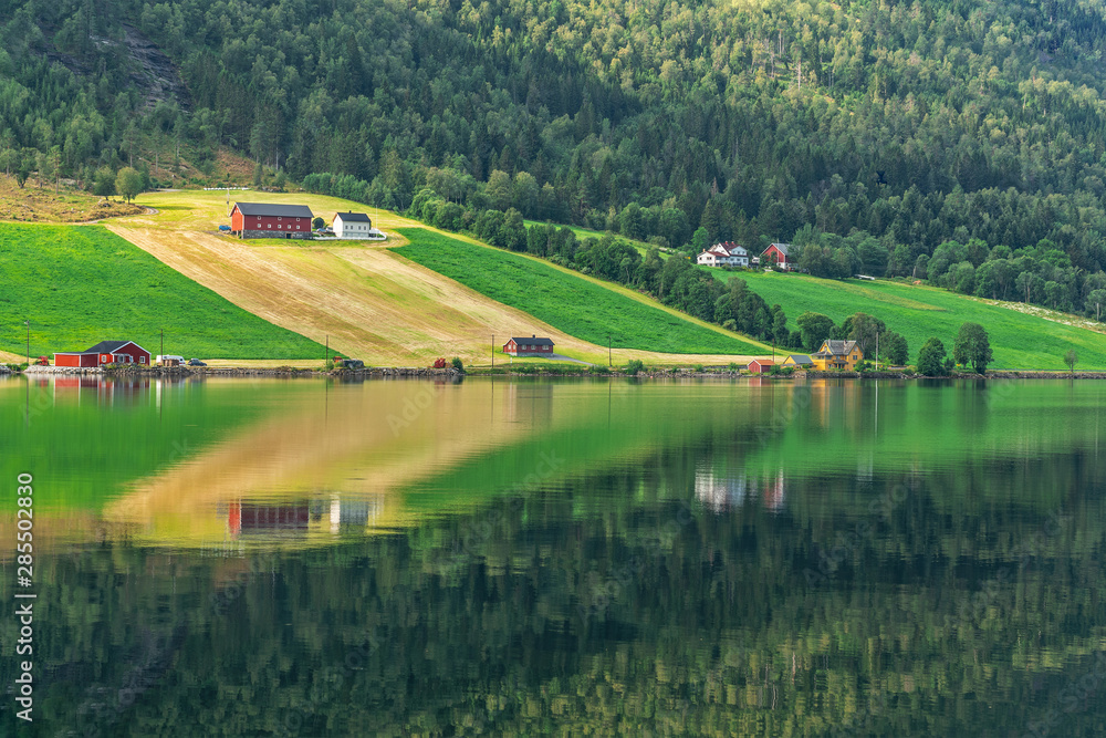 Green rural landscape view with reflection, countryside village houses, Norway