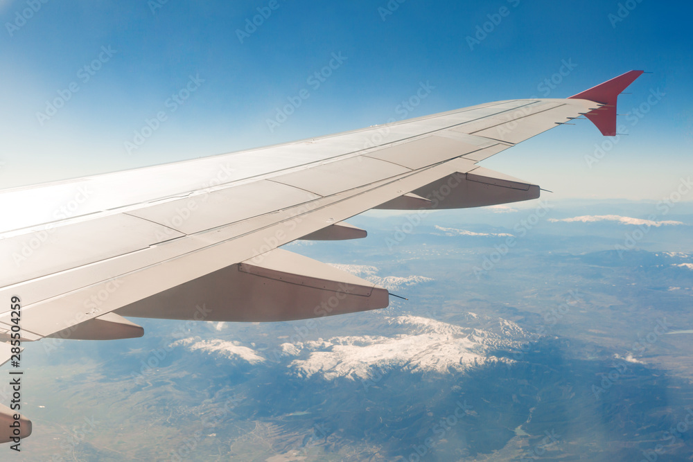 Aircraft wing on the clouds, flies on the mountains background Aircraft wing on the clouds, flies on the mountains background