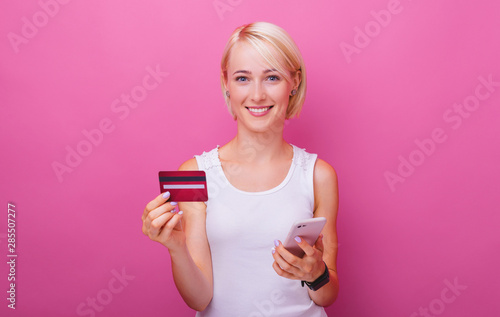 Portrait of confident young woman holding credit card and smartphone, web banking concept