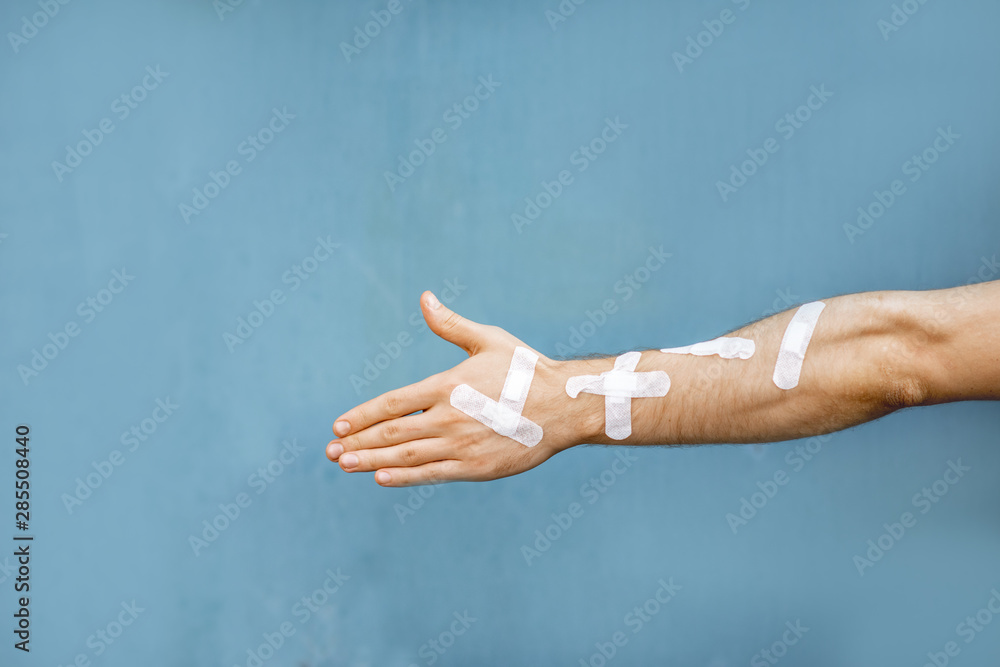 Male hand with medical patches on the blue background