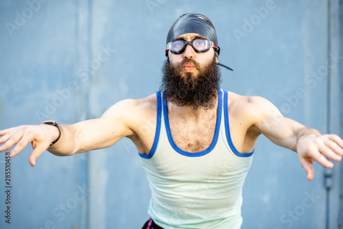 Portrait of a weird, old-fashioned swimmer dressed in 80s style with hat and swimming glasses on the yellow background