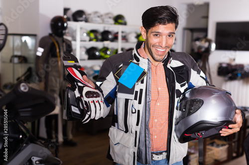 Happy man in moto jacket is choosing new gloves