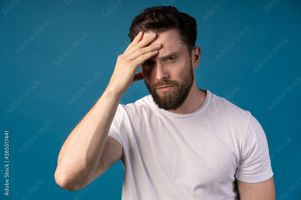 Close up portrait of frowning angry bearded man staring at camera isolated over blue background. . Portrait of a handsome man. Concept - anger, dissatisfaction. Close up portrait of frowning angry bearded man staring at camera isolated over blue background. . Portrait of a handsome man. Concept - anger, dissatisfaction.