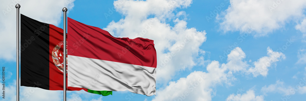 Naklejka premium Afghanistan and Monaco flag waving in the wind against white cloudy blue sky together. Diplomacy concept, international relations.