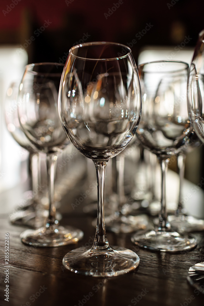 empty wine glasses. Beautiful new glasses for wine from glass stand in even rows on a wooden table in a restaurant. selective focus empty wine glasses. Beautiful new glasses for wine from glass stand in even rows on a wooden table in a restaurant. selective focus