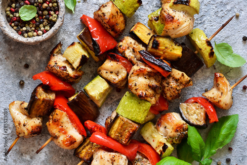 Barbecue of chicken on skewers with vegetables on stone background. Picnic.